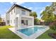 A modern home featuring a backyard pool surrounded by a marble tile patio and green lawn at 1521 Chestnut Ave, Winter Park, FL 32789