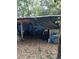 Dilapidated exterior shed covered in black and blue tarps and debris at 5429 Vanderlin St, Orlando, FL 32810