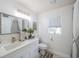 Bright bathroom with a white vanity, decorative mirror, and window at 3905 Westerham Dr, Clermont, FL 34711