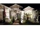 Exterior view of a well-lit home at night, showcasing landscape lighting and manicured greenery at 3905 Westerham Dr, Clermont, FL 34711