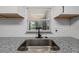 Close-up of kitchen sink features a stainless steel basin, dark faucet, granite countertop, and natural light at 219 Vermont Ave, St Cloud, FL 34769