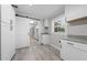 Bright laundry room features a sliding barn door, granite countertops, woodgrain floors, and white cabinets at 219 Vermont Ave, St Cloud, FL 34769