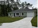 Charming single-story home featuring a well-manicured lawn, attached garage, and a classic, welcoming facade at 24202 Nw Aspen Ln, Dunnellon, FL 34432