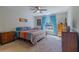Bright bedroom featuring a ceiling fan, a large window with blue curtains, and a colorful bedspread at 9085 Sw 202Nd Avenue Rd, Dunnellon, FL 34431