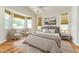 This bedroom is bright and airy with two chairs next to a window, a ceiling fan, and a painting above the bed at 777 Summit Greens Blvd, Clermont, FL 34711