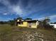 View of a single story house with large overgrown lot and trees on a sunny day at 1925 Laredo Dr, Deltona, FL 32738