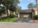 Tan home with an attached garage and a driveway leading up to the house surrounded by many trees at 116 Wild Holly Ln, Longwood, FL 32779