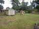 Spacious backyard featuring a storage shed, lush lawn, mature trees, and a playground for outdoor enjoyment at 3509 Lisa Ln, Lakeland, FL 33801
