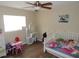 Cozy bedroom with wood-look floors, ceiling fan, a full-sized bed and a small play area at 3509 Lisa Ln, Lakeland, FL 33801