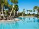 Resort-style pool area featuring mature landscaping, palm trees, and comfortable lounge chairs under sunny skies at 6185 Sw 89Th Ct, Ocala, FL 34481