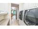 Laundry area featuring modern washer and dryer, white cabinetry, and views into the kitchen area at 9107 Sw 102Nd Cir, Ocala, FL 34481