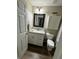 Bathroom with a granite vanity, mirror, toilet, and a wood-look floor at 10470 Sw 132Nd Ct, Dunnellon, FL 34432