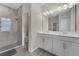 Bright bathroom features a double vanity with white cabinets and walk-in shower with gray tile and glass door at 1896 Napoli Dr, St Cloud, FL 34771