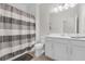 Neutral-toned bathroom features a shower-tub with a patterned shower curtain and a white vanity and toilet at 1896 Napoli Dr, St Cloud, FL 34771