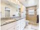 Bright bathroom features a granite countertop, tile shower, and white cabinets at 2641 Delcrest Dr, Orlando, FL 32817