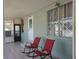 Relaxing front porch with two red rocking chairs and tiled floor for enjoying the outdoors at 6971 Pompeii Rd, Orlando, FL 32822