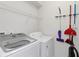 Functional laundry room featuring a modern washer and dryer with wire shelving and cleaning tools at 5545 Misty Oak Cir, Davenport, FL 33837
