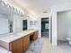 Bathroom featuring double sinks with wood cabinets, a vanity area, and an open door leading to another room at 9525 Southern Garden Cir, Altamonte Springs, FL 32714
