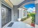Covered gray front porch area with black double doors, a welcome mat, and a view of green landscaping at 9525 Southern Garden Cir, Altamonte Springs, FL 32714