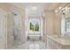 Elegant bathroom featuring marble floors, chandelier, soaking tub under arched window, and glass shower at 8707 Nw 31St Lane Rd, Ocala, FL 34482