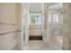 Luxurious bathroom with marble floors, stone shower, wood bench and a window that brings in light at 8707 Nw 31St Lane Rd, Ocala, FL 34482
