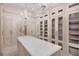 Elegant walk-in closet with custom cabinets, glass shelving, a marble island, and beautiful chandelier lighting at 8707 Nw 31St Lane Rd, Ocala, FL 34482