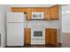 Close-up of kitchen appliances, including a white refrigerator and stove with wood cabinets at 294 Lake Doe Blvd, Apopka, FL 32703