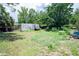 Overgrown backyard featuring grass, mature trees and outbuildings at 7043 Curtis Ave, Groveland, FL 34736