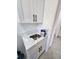 A laundry room with quartz countertop and sink with black fixtures and white cabinets at 13074 Sw 104Th Ln, Dunnellon, FL 34432