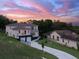Aerial view of a modern two-story home with balconies, two-car garage, and well-manicured lawn at sunset at 1841 Moorings Ct, Clermont, FL 34711