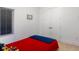 Simple yet cozy bedroom featuring neutral carpet and walls, plus a vibrant red bedspread with blue blanket at 1841 Moorings Ct, Clermont, FL 34711
