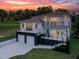 Stunning modern two-story home with balconies, two-car garage, and a manicured front yard at dusk at 1841 Moorings Ct, Clermont, FL 34711