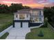 Modern two-story home featuring balconies, a two-car garage, and a beautifully landscaped front yard at dusk at 1841 Moorings Ct, Clermont, FL 34711