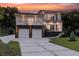 Modern two-story home featuring a two-car garage and a landscaped front yard, complemented by ambient outdoor lighting at 1841 Moorings Ct, Clermont, FL 34711