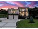 Stunning modern two-story home featuring a two-car garage and a beautifully landscaped front yard at dusk at 1841 Moorings Ct, Clermont, FL 34711