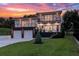 Modern two-story home with two-car garage, balconies, and landscaped front yard, illuminated by outdoor lighting at 1841 Moorings Ct, Clermont, FL 34711
