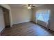 This bedroom features wood-look floors, a ceiling fan, and a window with stylish curtain, offering a cozy retreat at 507 Cloudcroft Dr, Deltona, FL 32738