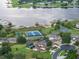 Aerial view of lakeside community featuring tennis courts and pool, and offering picturesque water views at 17426 Tailfeather Ct, Clermont, FL 34711