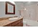 Bathroom featuring granite counters, wood cabinets, and a shower with a glass door at 17426 Tailfeather Ct, Clermont, FL 34711