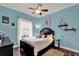 Cozy bedroom with a ceiling fan, a black bed frame, and blue walls at 17426 Tailfeather Ct, Clermont, FL 34711