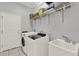 Functional laundry room with modern washer and dryer, sink, and ample storage shelving at 17426 Tailfeather Ct, Clermont, FL 34711