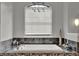A large soaking tub with decorative stone work under an arched window with blinds at 17426 Tailfeather Ct, Clermont, FL 34711