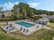 Community pool with sun loungers, tables, and a playground in a fenced area, surrounded by mature trees at 17426 Tailfeather Ct, Clermont, FL 34711