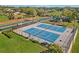 Aerial view of blue tennis courts with a playground nearby and well-maintained green spaces at 17426 Tailfeather Ct, Clermont, FL 34711
