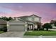 Charming two-story home with a well-manicured lawn, a brick driveway, and a two-car garage under a colorful sky at 1485 Waukon Cir, Casselberry, FL 32707