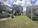 View of the green backyard with trees, overgrown foliage, and screened in enclosure at 2921 Blackburn Ave, Deltona, FL 32738