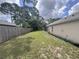 Backyard with green grass, trees, and partial view of the home's exterior with fence in the background at 2921 Blackburn Ave, Deltona, FL 32738