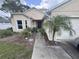 Inviting front entrance with a garden, decorative palm tree, and a covered walkway leading to the front door at 2921 Blackburn Ave, Deltona, FL 32738