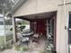 Covered patio area in need of cleaning, featuring various furniture and items, with an adjacent screened enclosure at 2921 Blackburn Ave, Deltona, FL 32738