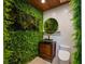 This bathroom features a unique living wall, round mirror, wooden vanity and a modern toilet at 13450 E Lake Mary Jane Rd, Orlando, FL 32832